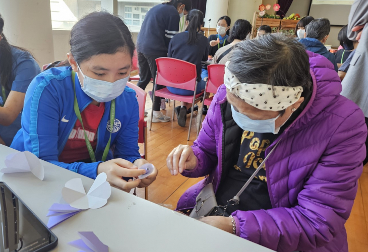 學生在康恩園的服務活動中，耐心地教導中心會員製作小手工